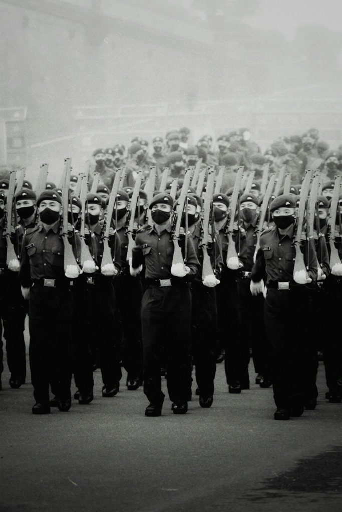 A black and white photo of soldiers in uniform marching in formation during a military parade.