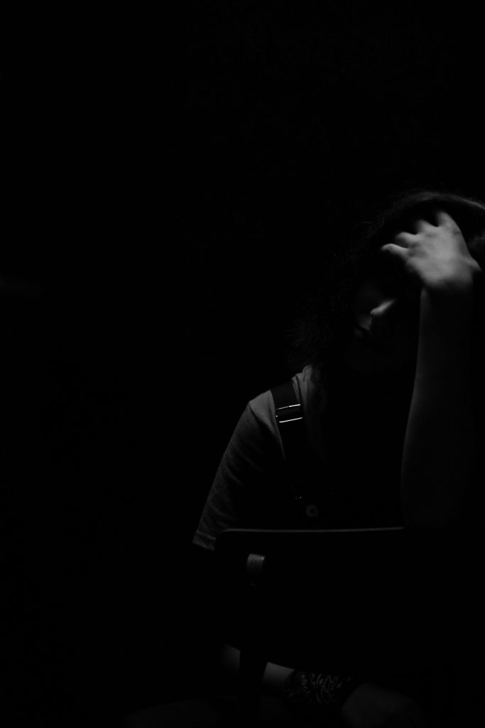 Dramatic black and white portrait capturing a pensive mood in a dimly lit studio.