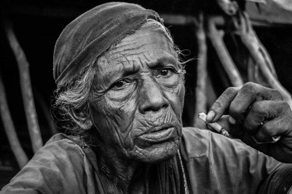 Black and white portrait of an elderly woman with a cigarette, evoking depth and emotion.