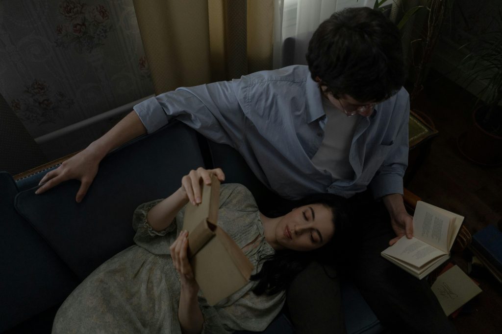 Couple enjoying a relaxing moment at home, reading books together on a sofa.