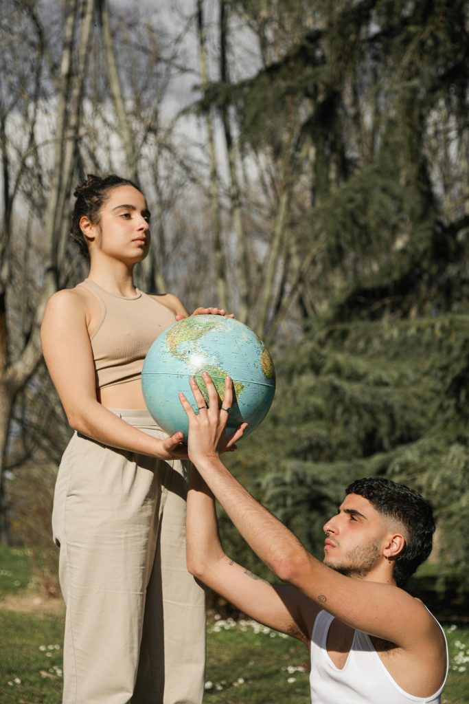 Two adults expressing unity and global awareness by holding a globe outdoors.