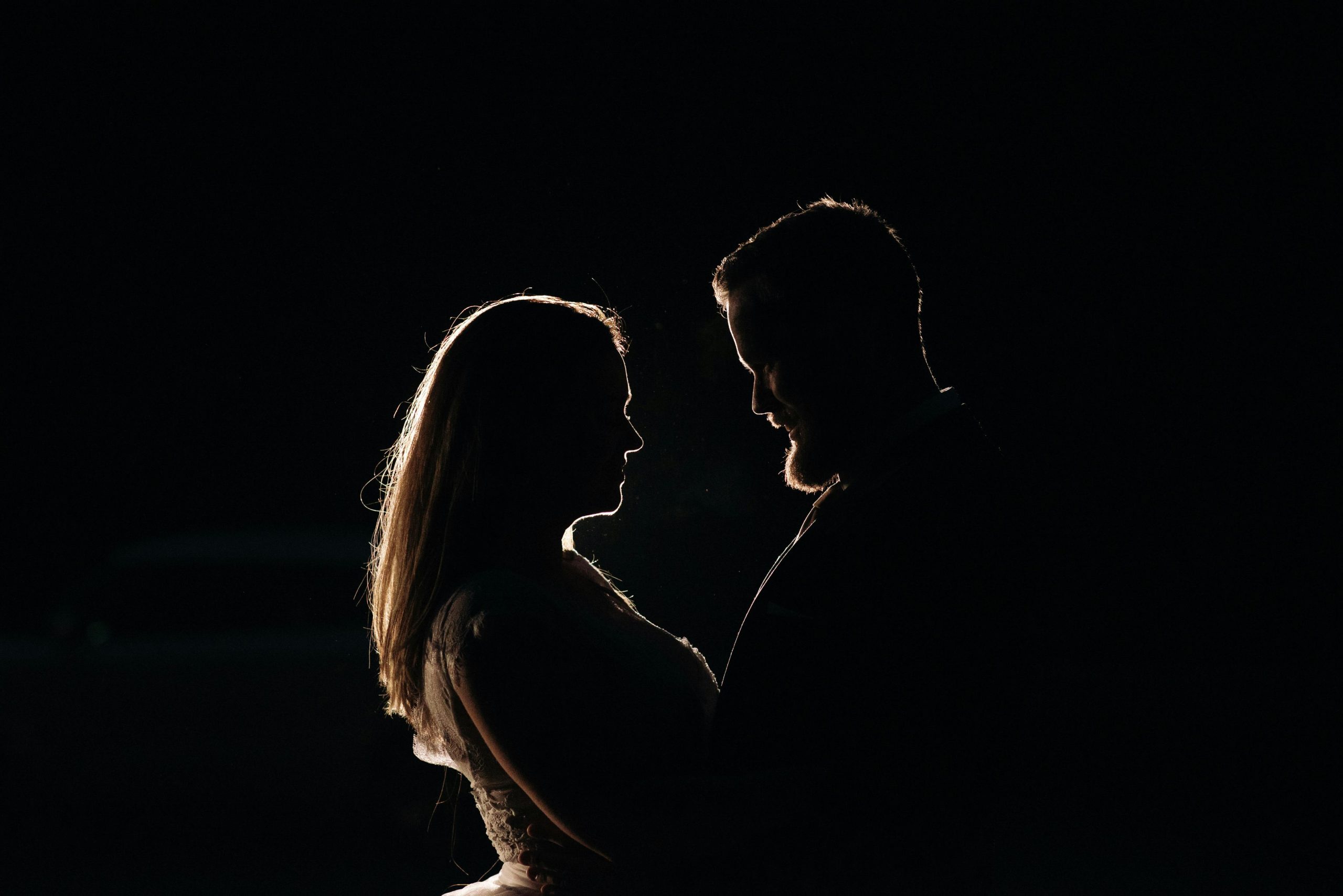 Silhouette of a couple embracing in a dark room, capturing a moment of intimacy and connection.